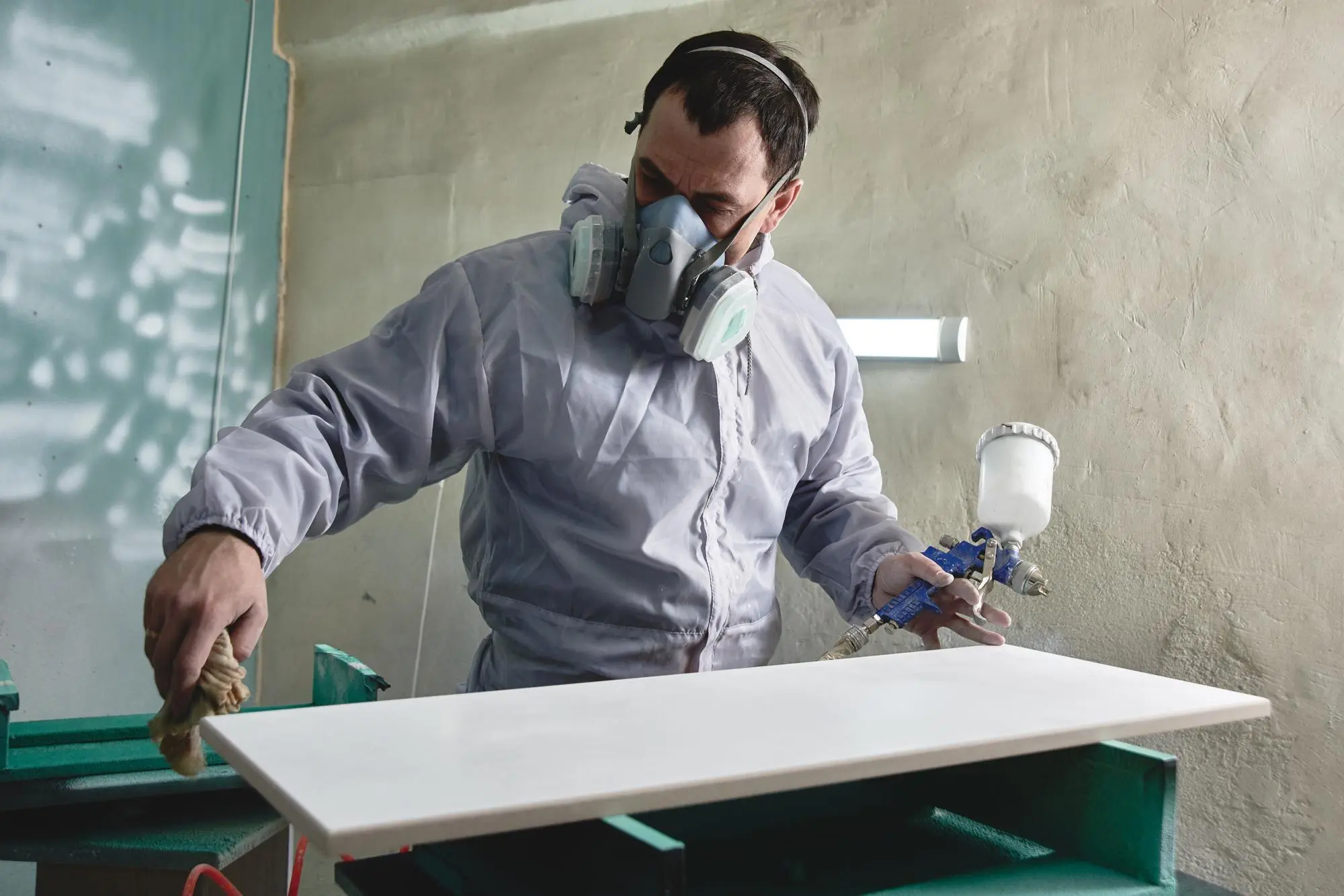 process production manufacture wooden furniture factory worker man overalls paints wood with paint s